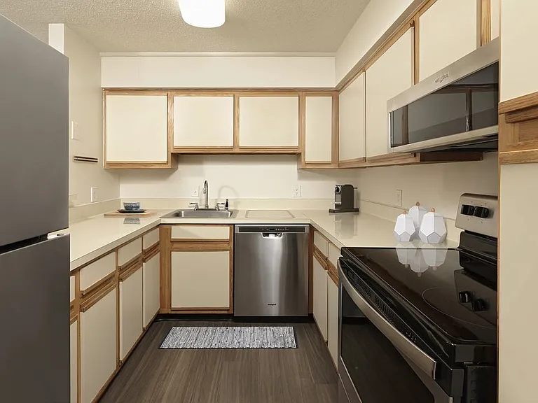 Finish Package I kitchen with beige cabinetry and countertops, stainless steel appliances and hard surface plank flooring