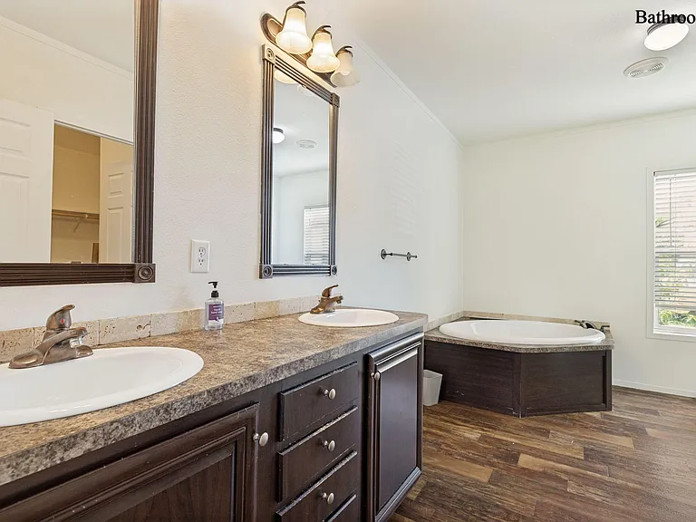 Spacious bathroom with dual-sink vanity, large mirrors, and a soaking tub, plus a window for added ventilation.