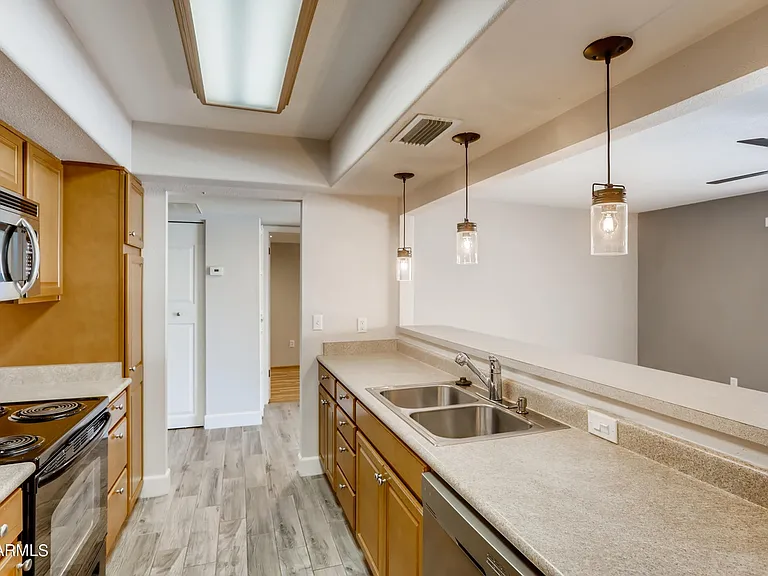 Sleek kitchen with double-sink, garbage disposal, dishwasher, microwave, stove/oven & fridge.