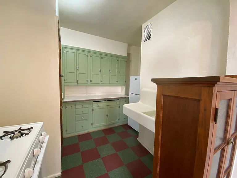The kitchen blends vintage charm with practicality, showcasing mint green cabinetry, bold retro tile flooring, and warm wood accents. With abundant built-in storage and timeless architectural details, the space feels distinctive and inviting.