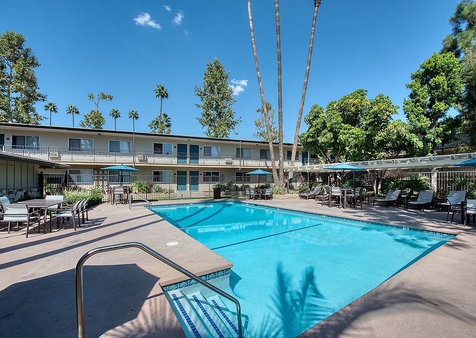 Swimming pool surrounded by lounge chairs, umbrellas, and tables.