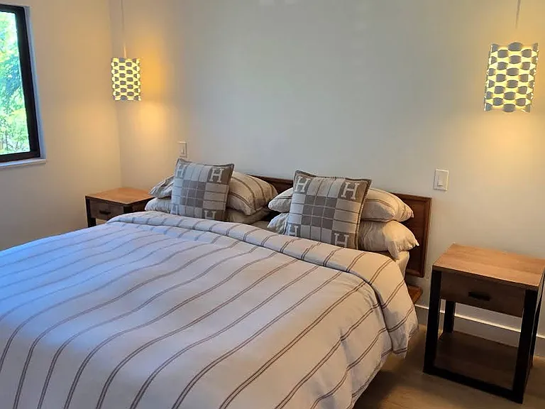 King size Norwegian-style bed, wood bedside tables, white pendant lights & floor-to-ceiling custom white soft-panel window treatments