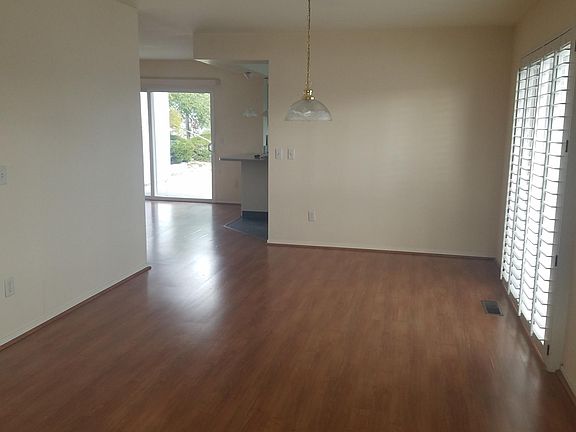 dining area, sliding door and shutters at right to small deck- looking through family room out sliding door, and kitchen (behind