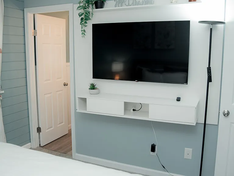 A serene space featuring soft blue tones, delicate floral art, and a plush, comfortable bed.
