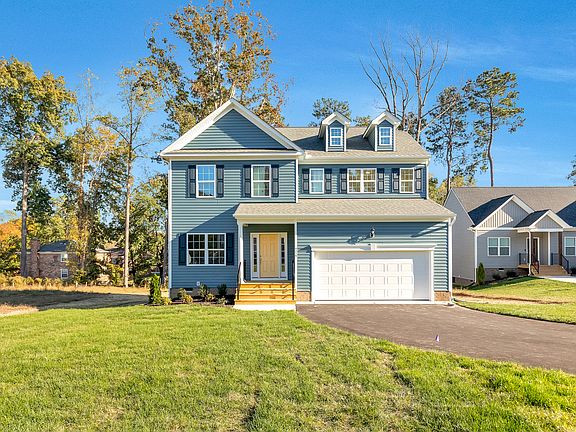 Two-story blue house with white trim and garage on sunny, grassy Lot 29 in Poplar Village.