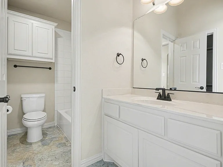 Bathroom featuring a single vanity with white cabinetry, a light-toned countertop, and a rectangular undermount sink with a matte black faucet