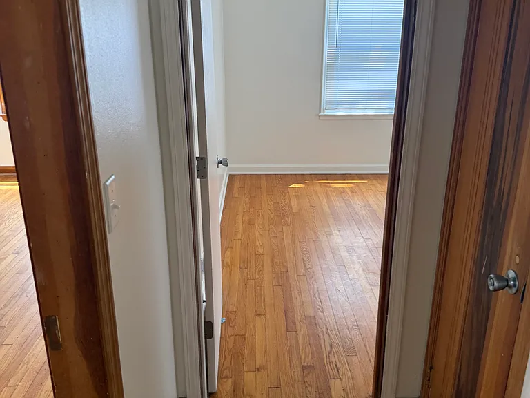 Hall looking into a bedroom on main floor with hardwood new windows & blinds