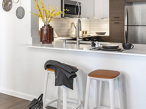 Apartment Kitchen with Stainless Steel Appliances, quartz counters and wood floors.