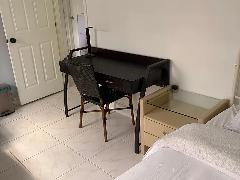 Private bedroom with tile flooring, a work desk, and convenient bedside storage for everyday essentials.