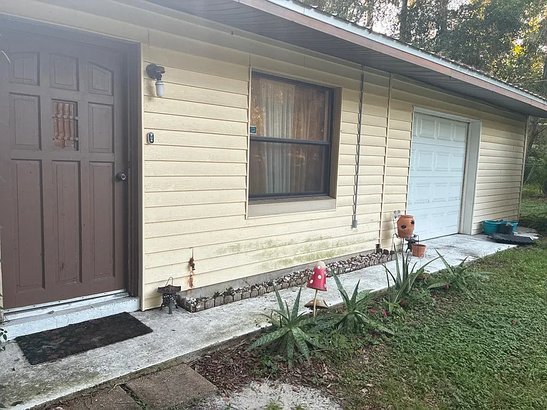 Ground-level entry with a covered walkway, front window, and convenient access to an attached garage.