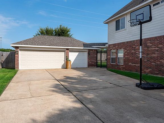 The driveway is separated from the backyard with a tall iron gate.