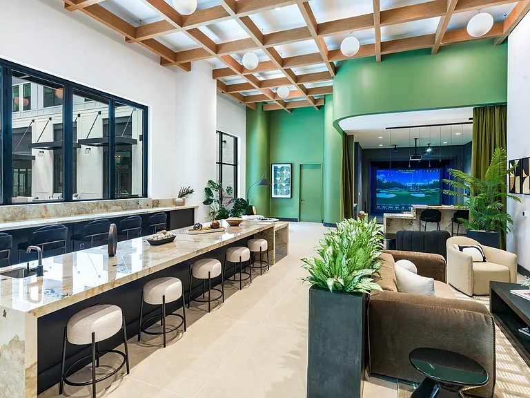 Spacious and stylish, the resident lounge at Modera Riverview features a modern demonstration kitchen, ample seating, and access to the golf simulator area.
