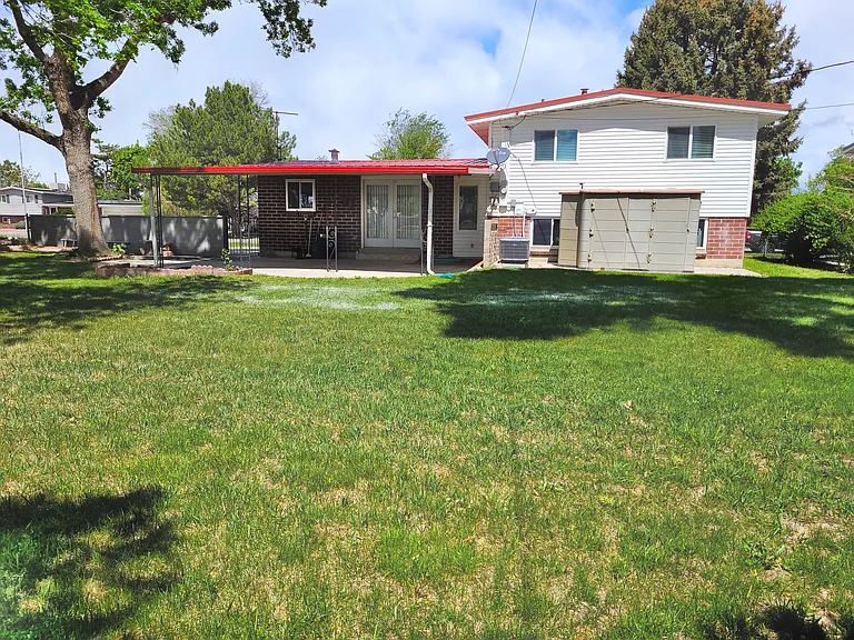 Large fenced backyard next to school with 2 sheds and covered patio