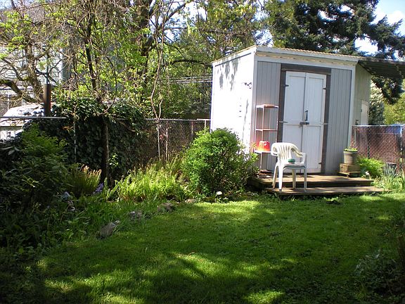 Back fenced yard with sturdy and sweet shed.