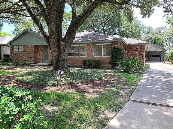 Detached garage with built-in carport. Majestic Oak trees in front.