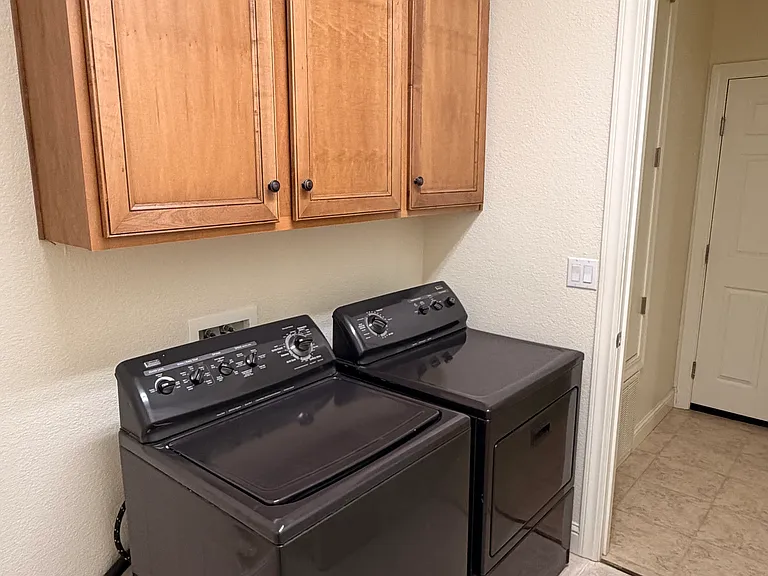 Large laundry room with cabinets and washer/dryer for tenant use.