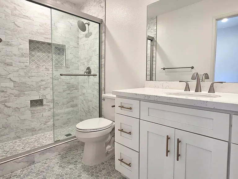 Remodeled primary suite bathroom with marble flooring.