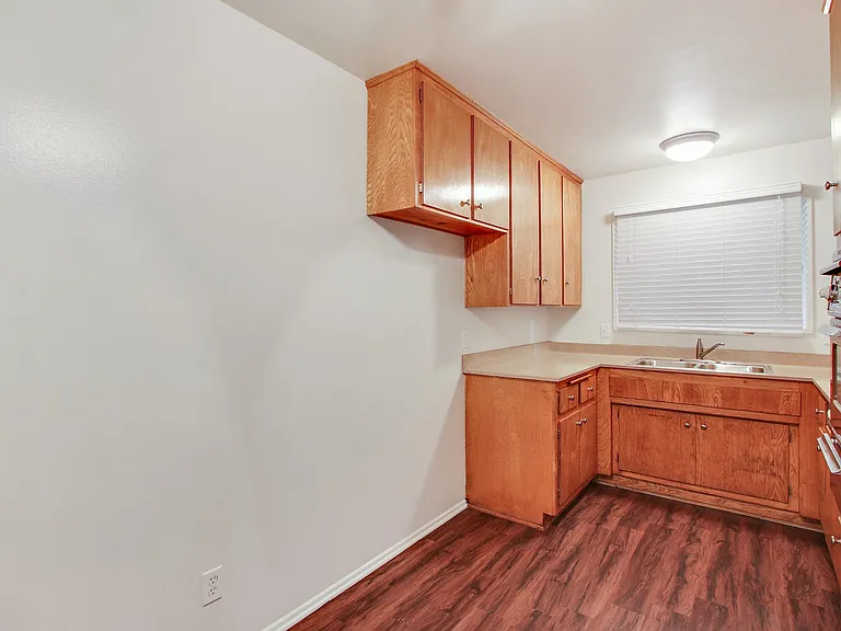 Kitchen with double stainless steel kitchen sink, quartz countertops, stainless steel Microwave oven on the right, wood kitchen cabinets, and wood style floors