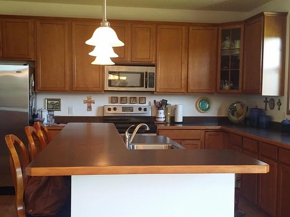 Large kitchen with cherry cabinetry and 2 tier island with stainless steel appliances.