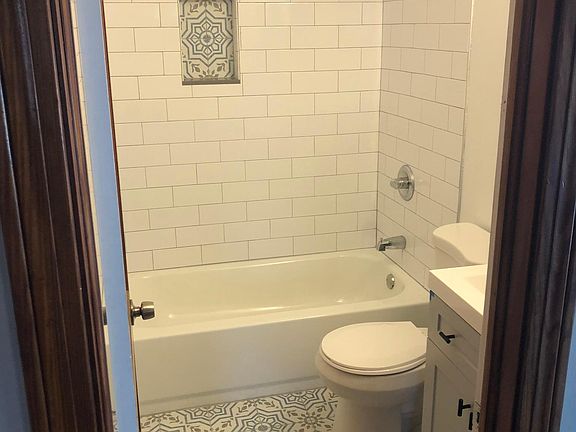 Newly updated bathroom with decorative tile floor, subway tile shower, and new vanity and mirror.