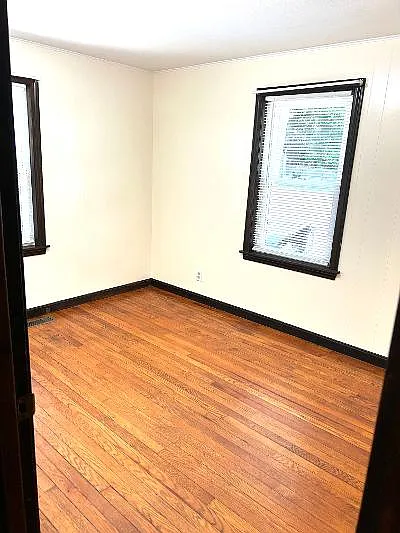 Den with hardwood floor.