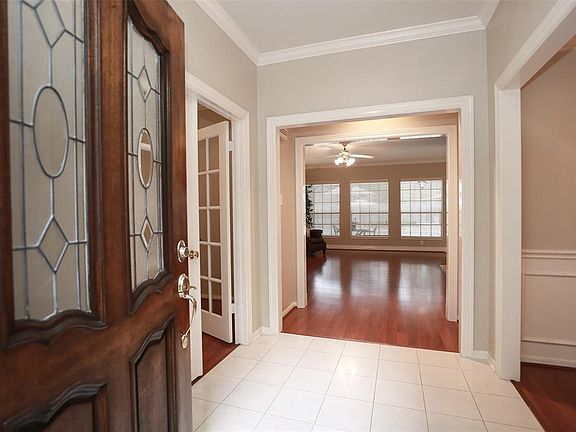 SOLID WOOD FRONT DOOR WITH LEAD GLASS INSERTS - The entry to the home features tile floors, crown molding and ceiling light. The den is in view.