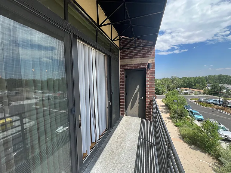 Large covered balcony with room for a grill and sitting/dining area looking out toward Flatirons.