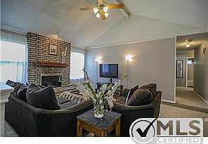Living room has ceiling fan and wood burning fireplace