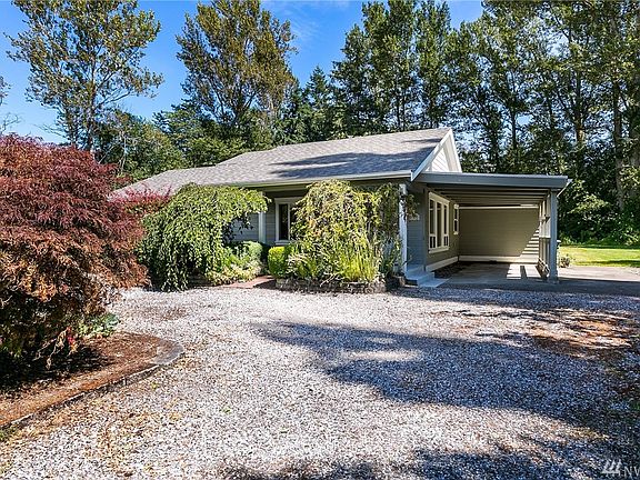 Covered patio off front porch framed by mature landscaping