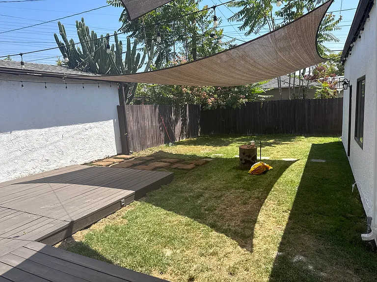 Private fenced backyard with a spacious patio, two large Sunbrella shades, and plenty of room for outdoor entertaining.