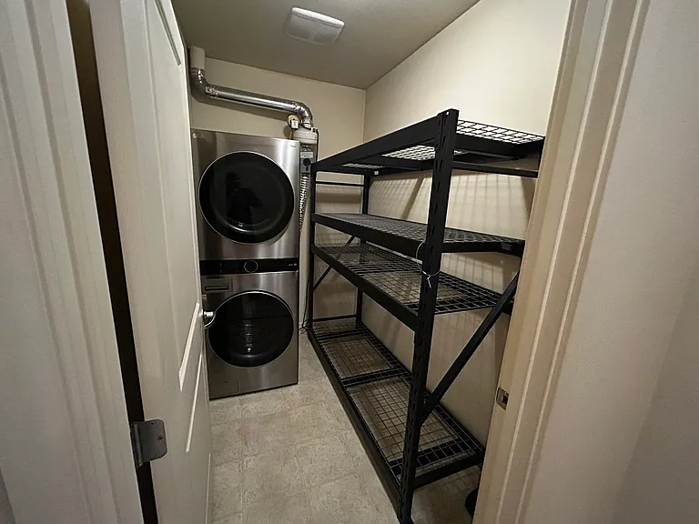 Utility room with storage rack and washer/dryer. We can remove the storage rack if preferred, as it can be a bit tight.