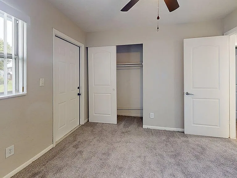 Inviting bedroom with plush carpet, a spacious closet, and large window offering natural light and tranquil views.