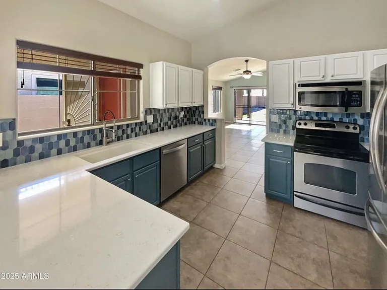 Spacious kitchen with generous counter space, ample cabinetry, and stainless-steel appliances, opening to the patio.