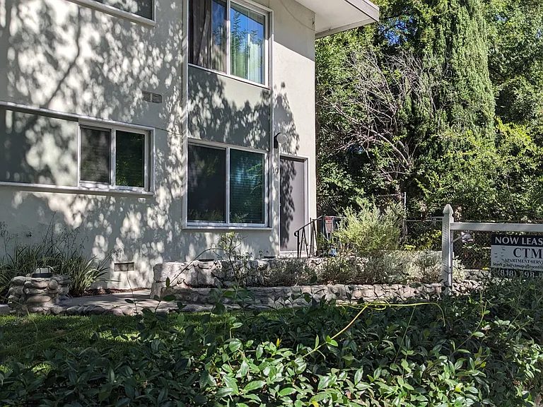 Stone walls and lush gardens and mature trees at Los Robles Apartments in Pasadena, California.