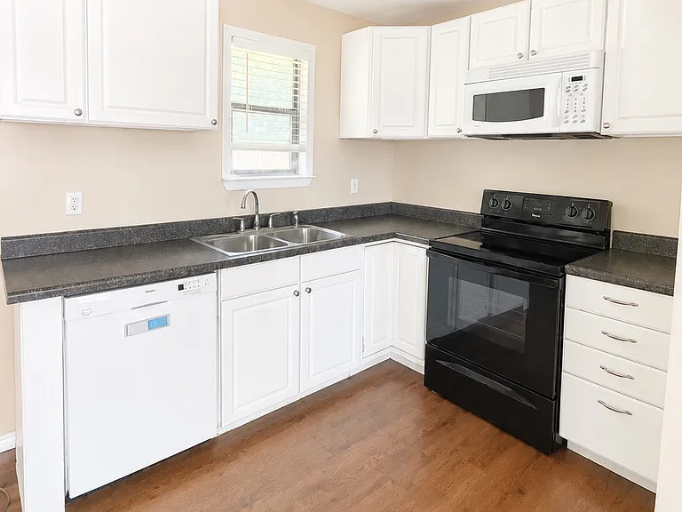 Bright Kitchen featuring white cabinetry, ample counter space, and modern appliances.