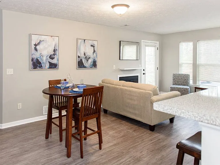 View of great room from the kitchen breakfast bar showing dining area and living area with fireplace and large, bright windows