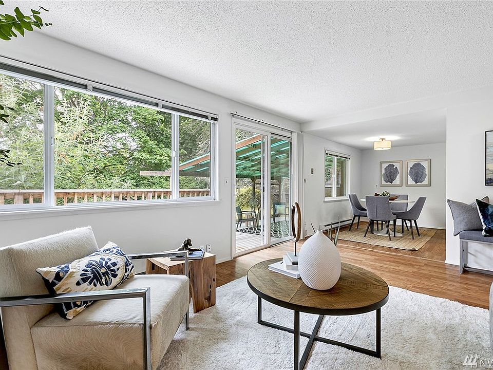 The living room with walls of glass opens onto the dining room and outside to the west facing sunny deck which overlooks the oversized in town backyard!