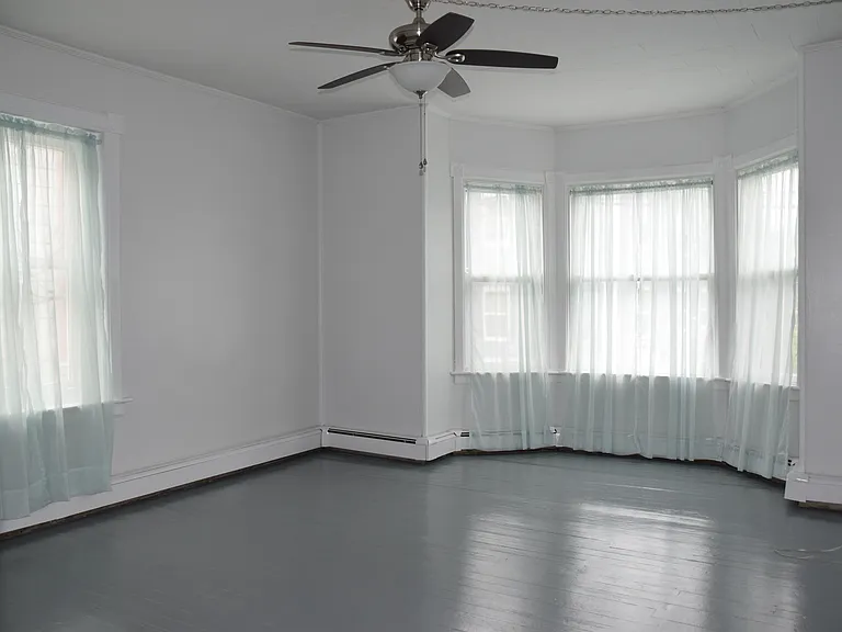 Large living room with ceiling fan, bay windows, cable ready.