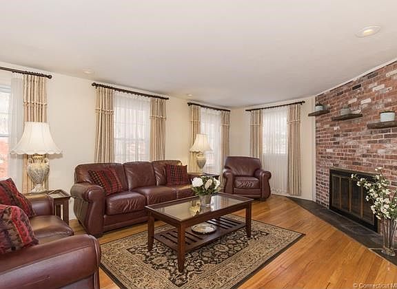 living room features floor to ceiling brick fireplace and hardwood flooring