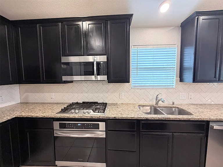 Spacious, modern kitchen featuring stainless steel appliances, custom cabinetry, elegant granite countertops, and a large center island perfect for both meal preparation and casual dining.