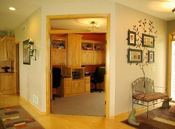 French doors into dual desk office w/ media center & deep bookshelf.