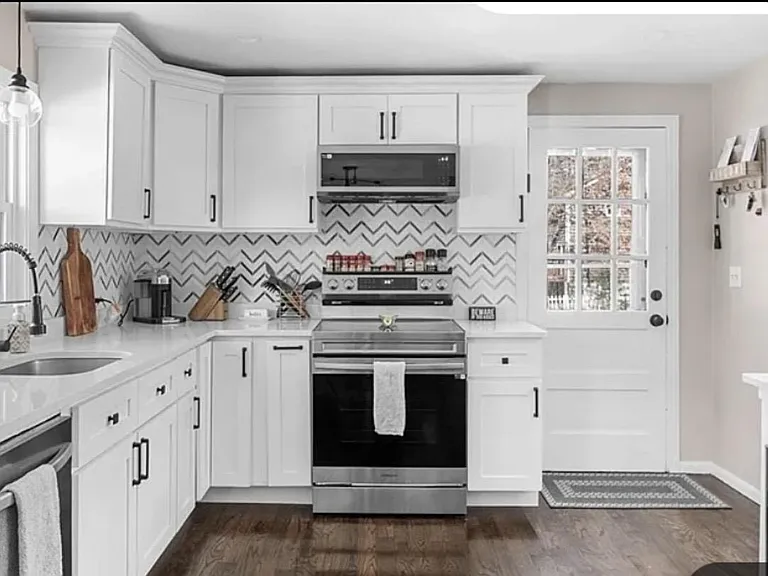 Updated kitchen with shaker cabinetry, stainless steel range and microwave, and ample counter space for meal prep.