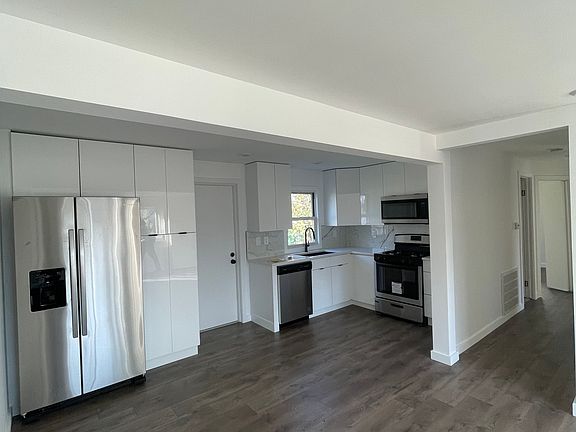 Modern kitchen with quartz countertops, marble-style backsplash, and stainless-steel appliances.