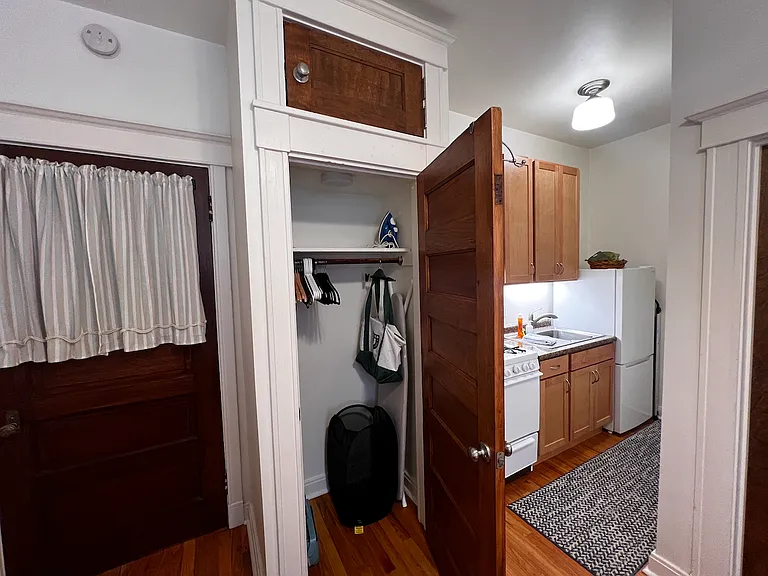 Closet has ironing board, iron, and overhead storage.