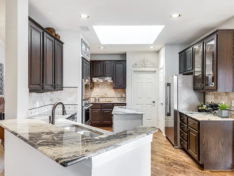 Kitchen peninsula, beautiful stone/granite countertops, a skylight and dark brown cabinets.