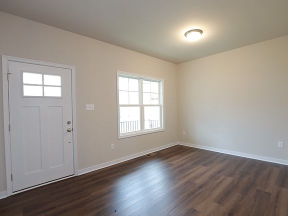 Empty room with wooden floors, a window, and a white door on Lot 31 in Poplar Village under a ceilin
