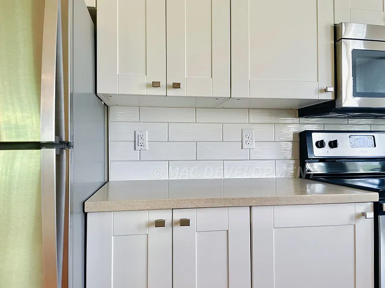 Stainless steel appliances, Quartz countertops and modern white wave subway tile adorn the kitchen