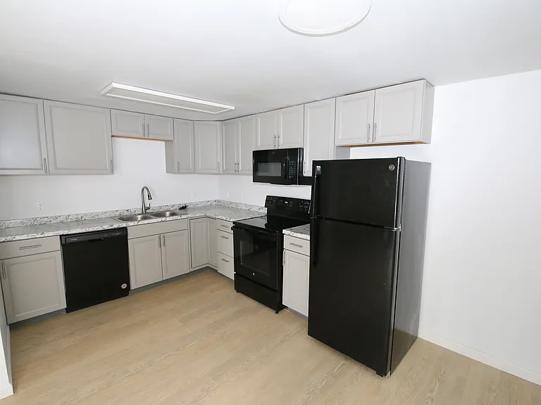 Modern kitchen with sleek black appliances, elegant gray cabinets, and a stylish marble countertop.