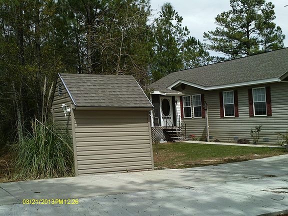 Looking at front of house past driveway and well-house