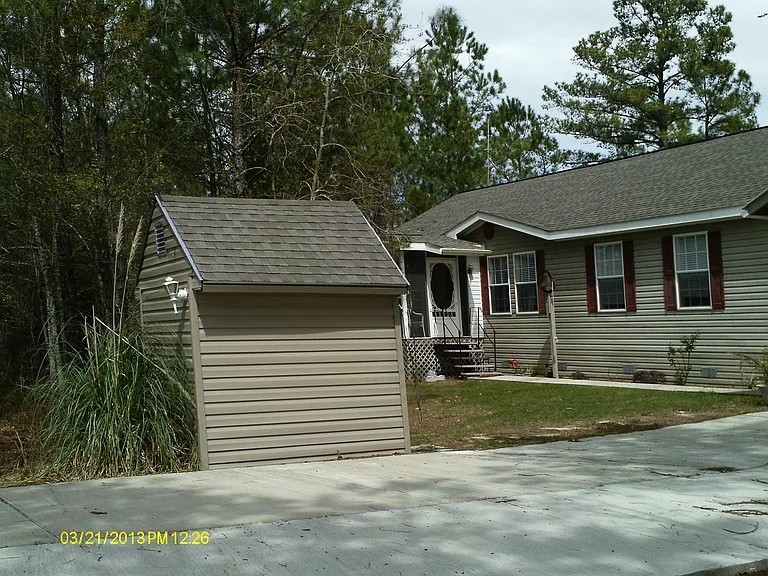 Looking at front of house past driveway and well-house